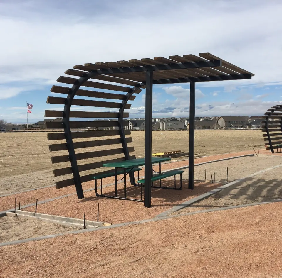 Curved steel shade structure over a picnic table