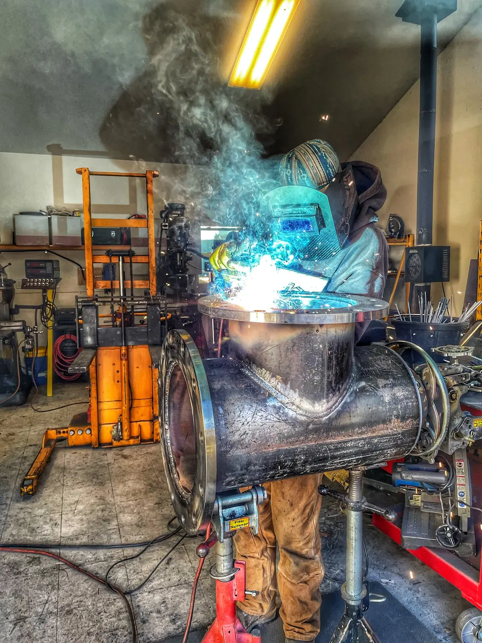 Welder fabricating a large flanged pipe tee in the SteelCraft shop